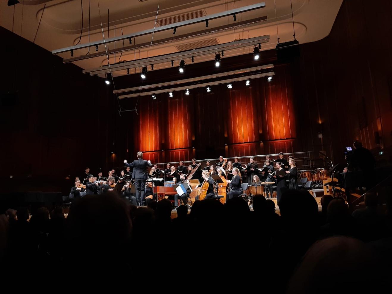 im Konzert: Blick auf Bühne mit Dirigenten, Orchester und Chor