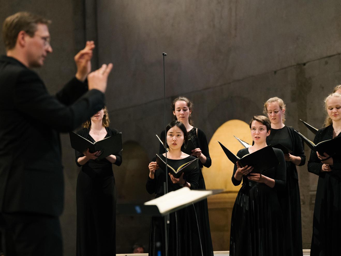 Konzert des Kammerchors im Kloster Eberbach. Im Hintergrund Sängerinnen, im Vordergrund (unscharf) Prof. Florian Lohmann.