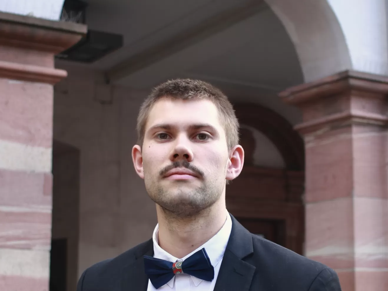 Porträt von Jonathan Ernst mit Anzug, Fliege und Trompete