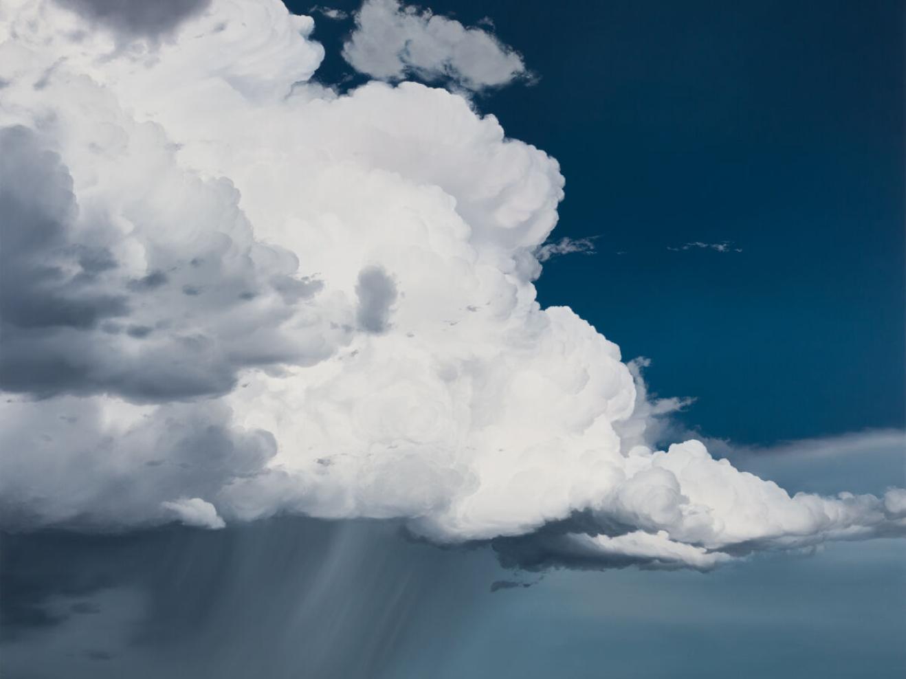 Große weiße Wolke vor blauem Hintergrund mit Regen.