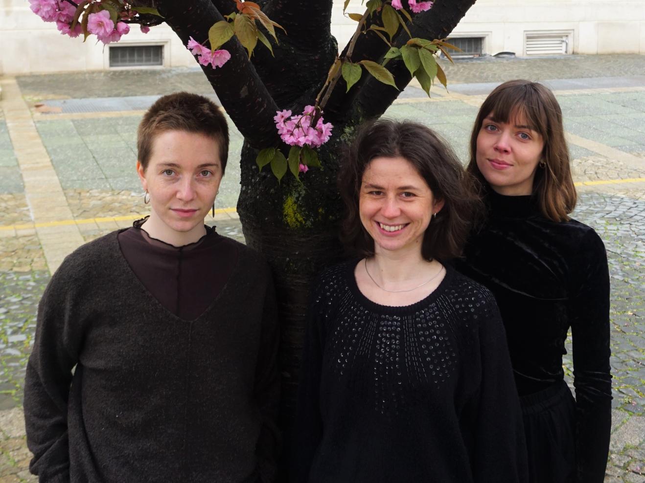 Die drei Musikerinnen des Trio Evviva stehen unter einem blühenden Kirschbaum