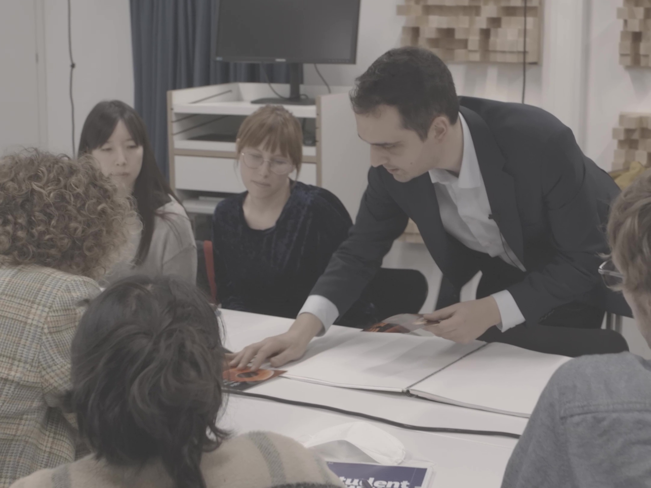 Seminar mit Koka Nikoladze, der sich über den Tisch beugt und den Studierenden etwas zeigt.