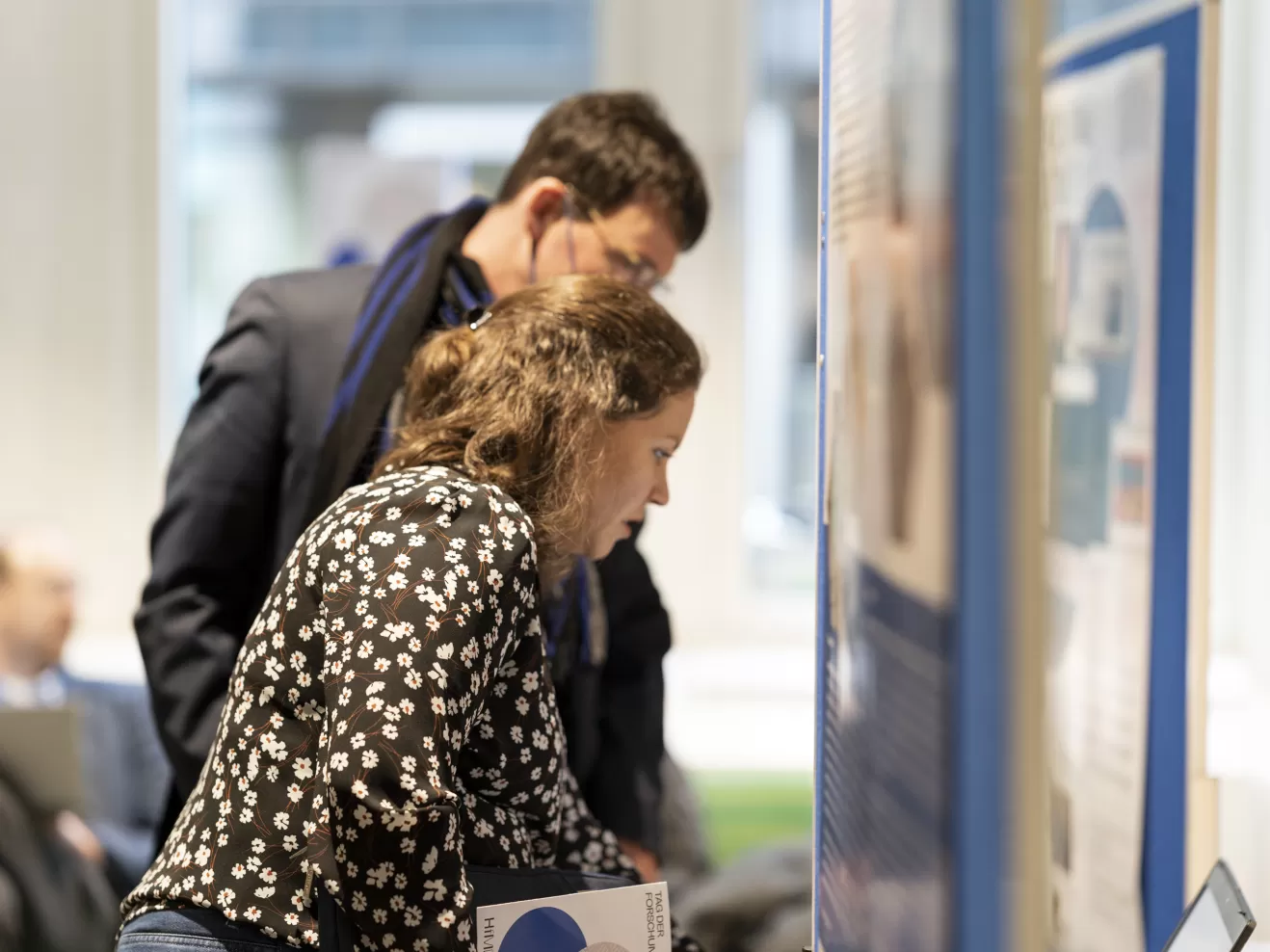 Zwei Personen blicken auf eine Plakatwand am Tag der Forschung