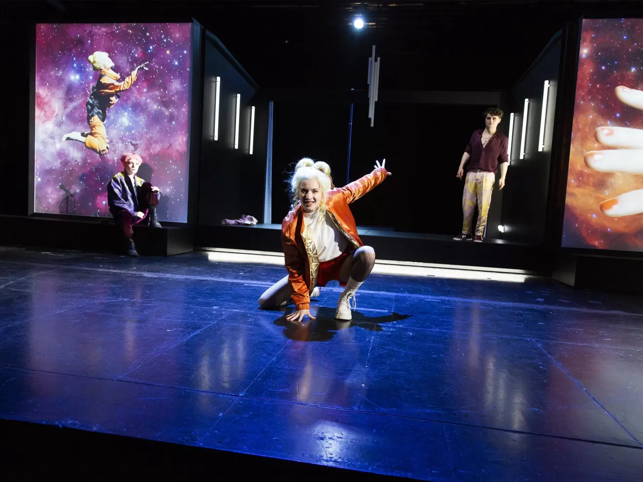 Schauspielerin in dynamischer Pose in der Mitte einer Bühne.