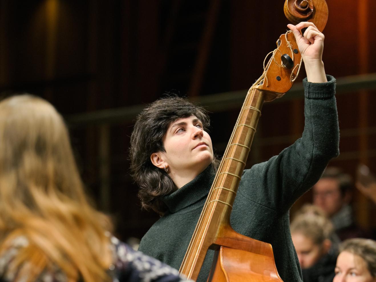 Eine Person stimmt ein Instrument auf der Bühne