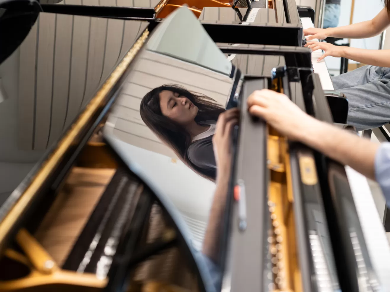 Klavier-Einzelunterricht: Das Gesicht der Studentin spiegelt sich im glänzenden Lack des Flügels.