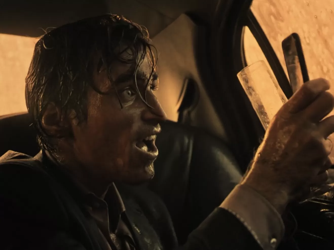 Mann in einem Auto fotografiert mit dem Handy blutigen Regen vor dem Autofenster.