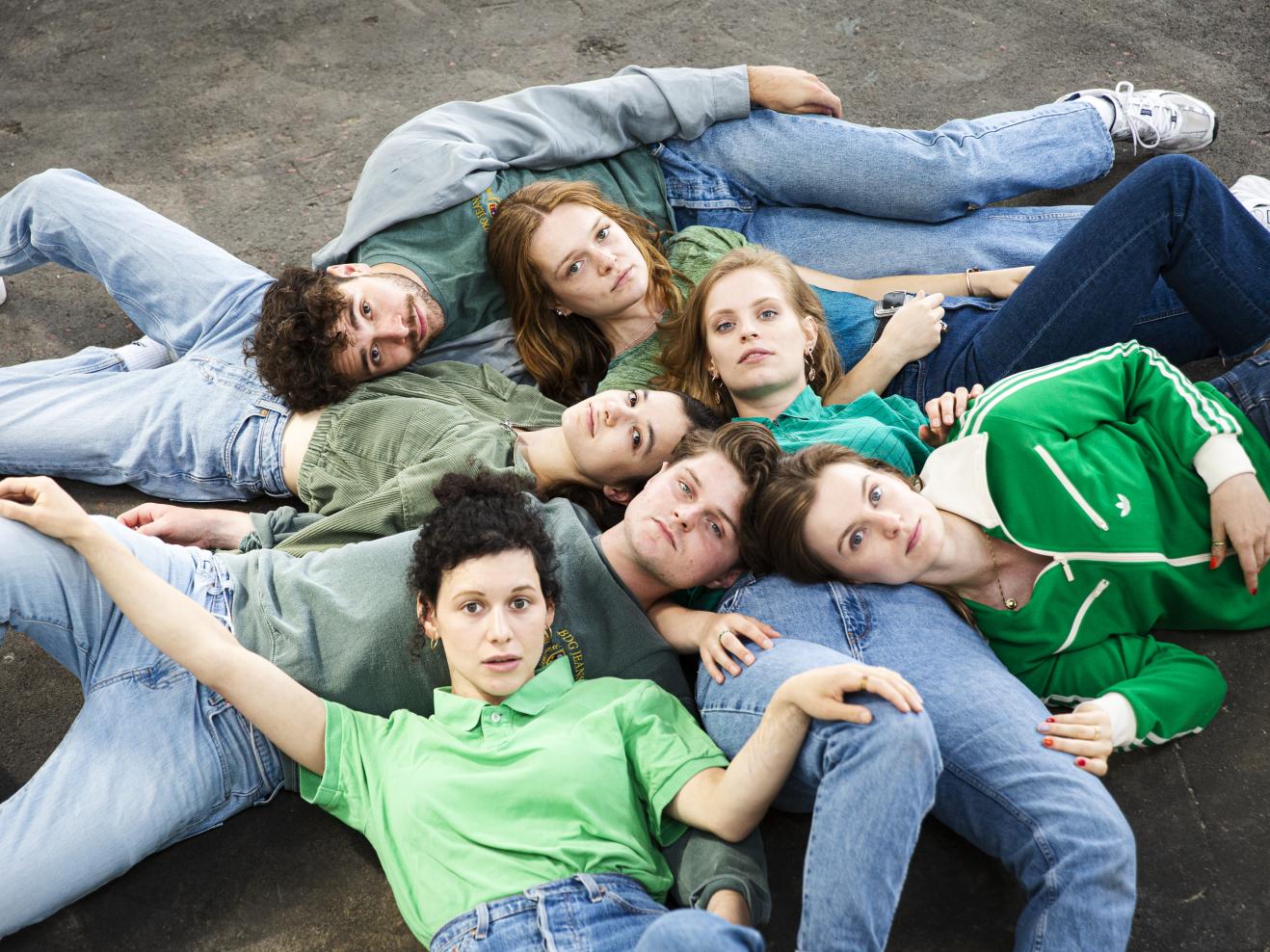 Sieben Studierende liegen auf dem Boden zusammen.