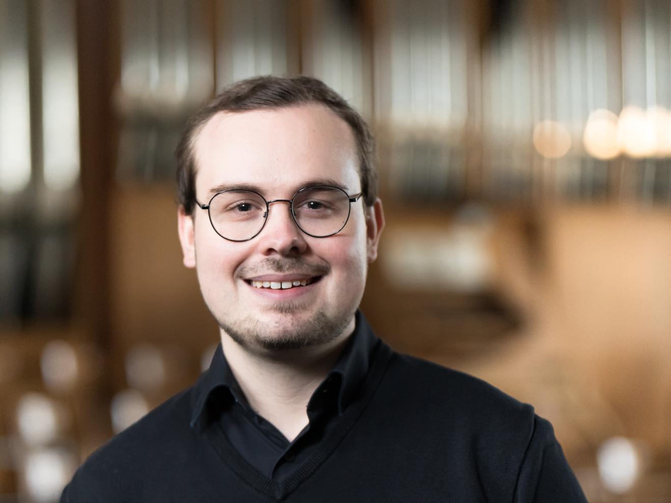 Lukas Euler mit verschwommener Orgel im Hintergrund