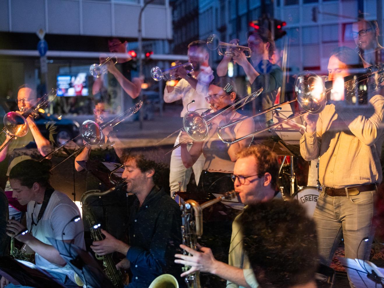 Bigband-Musiker*innen im Club ono2, durch das Fenster betrachtet