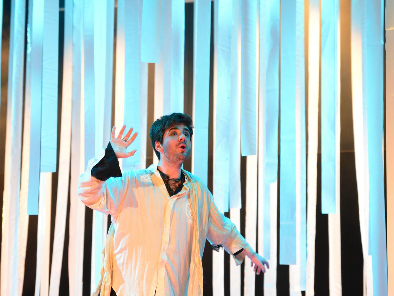 Sänger in einer Musiktheaterproduktion umgeben von blauem Licht
