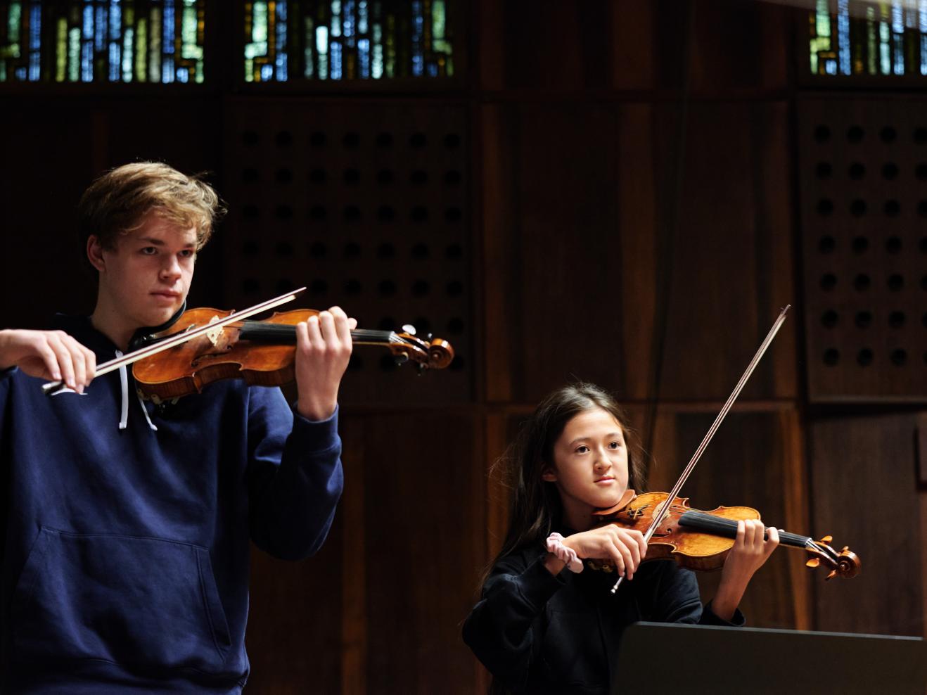 Zwei Jungstudierende spielen Violine bei einer Probe im Großen Saal.