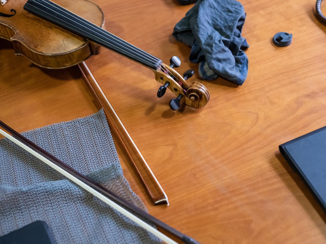 Eine Violine und zwei Streicherbögen liegen auf einem Holztisch.