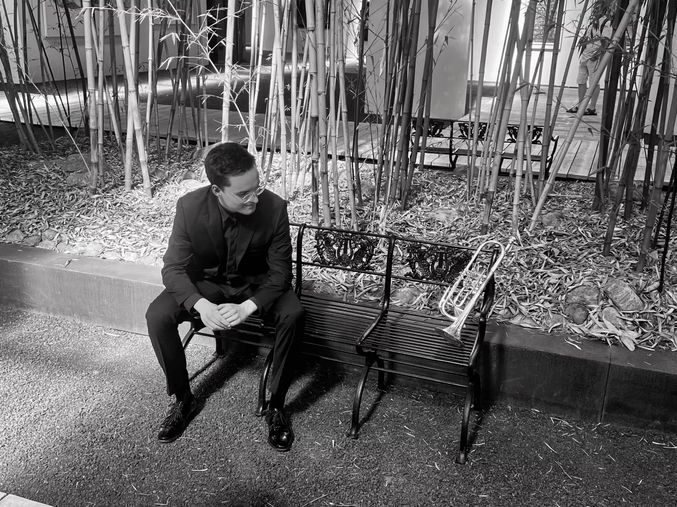 Sebastian Kellner sitzt auf einer Bank und schaut seine Tompete an, die ebenfalls auf der Bank liegt