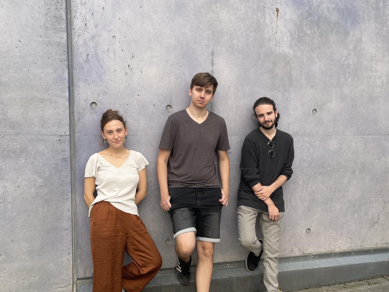Die drei Musiker*innen des Sören Riesner Trios lehnen an einer grauen Betonwand.