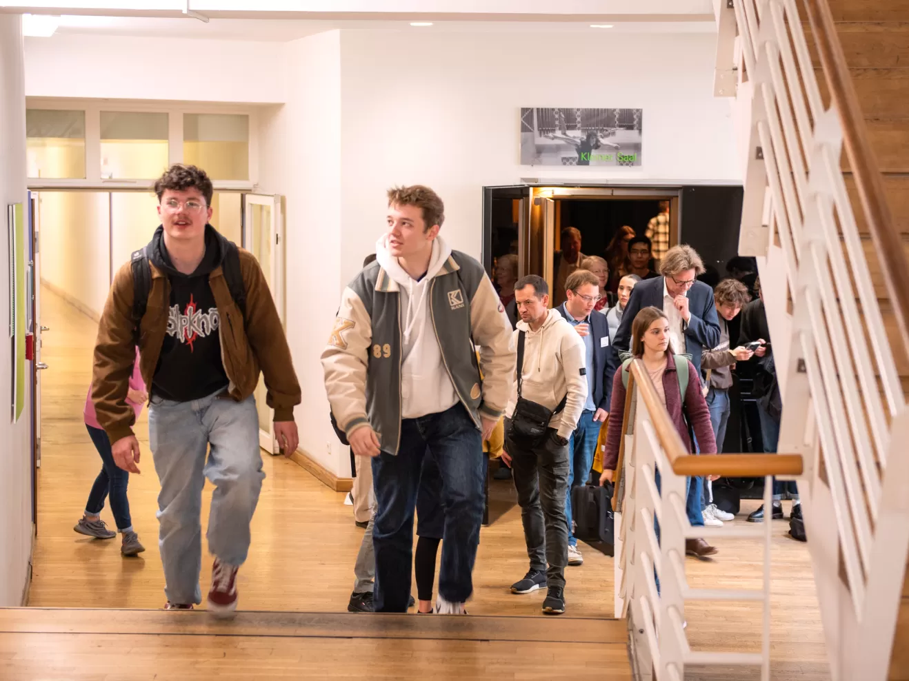 Eine Gruppe von Schüler*innen läuft beim Infotag Lehramt durch das Foyer und Treppenhaus der HfMDK Frankfurt.