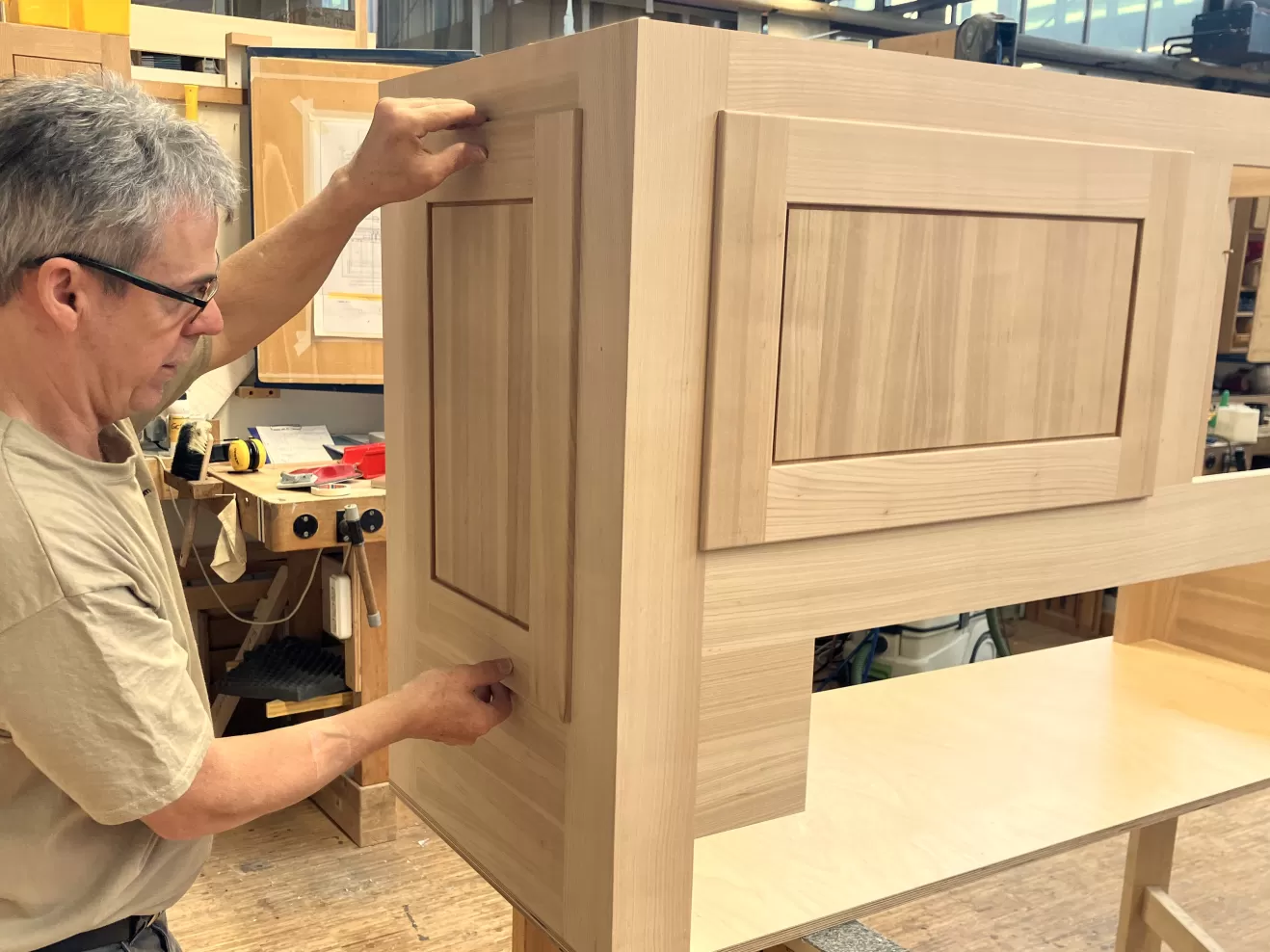 Ein Mitarbeiter setzt weitere Holzteile in die Aussparungen im Gehäuse ein.