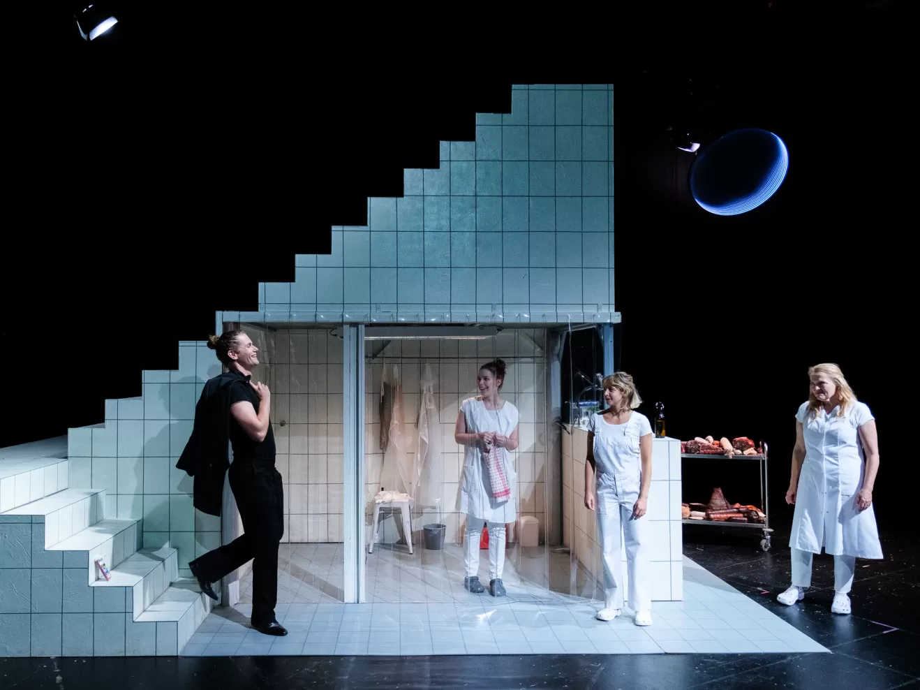 Mehrere Personen stehen in einem weiß gefliesten Raum.