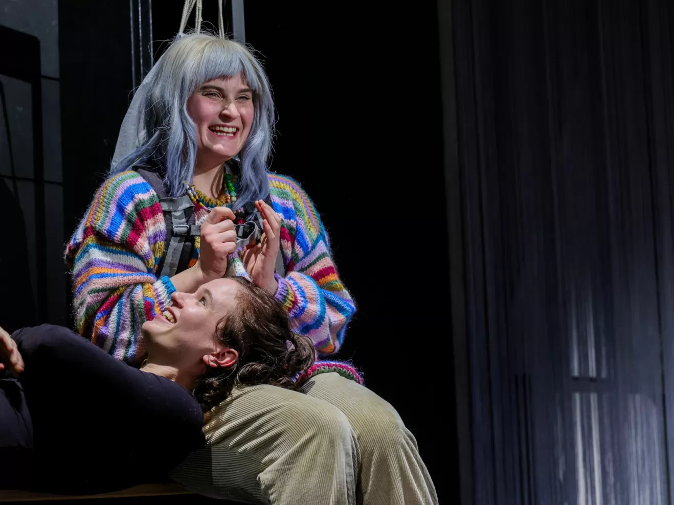 Eine Frau sitzt und eine andere Frau liegt mit dem Kopf auf ihrem Schoß.