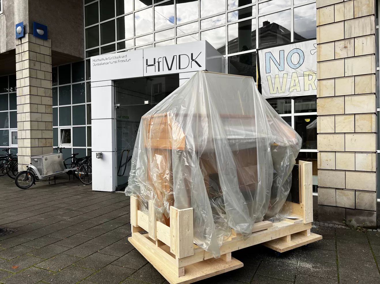 Der Spieltisch steht, unter einer Plane verpackt, vor dem Haupteingang der HfMDK.