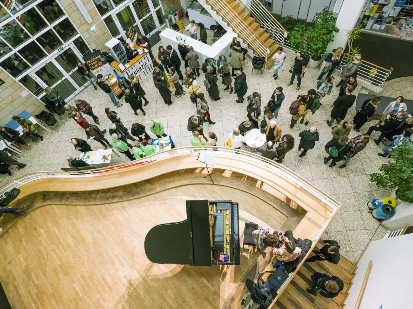 Im Foyer stehen viele Veranstaltungsgäste, auf der Empore vor dem Kleinen Saal steht ein Flügel. Das Bild ist von oben fotografiert.