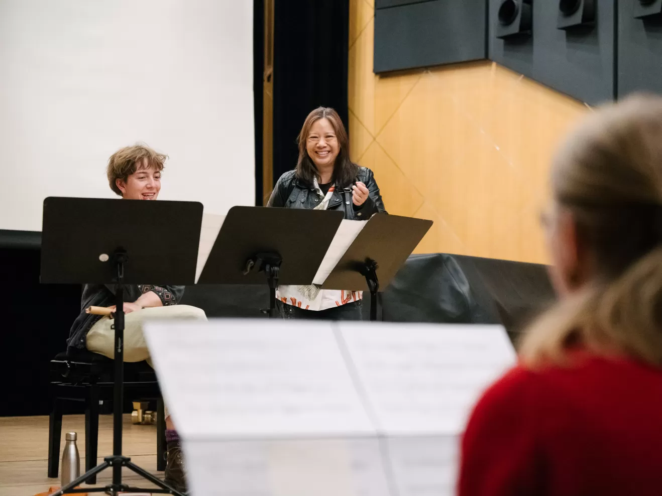 Liza Lim unterrichtet lächelnd zwei Studierende, die hinter ihren Notenpulten sitzen