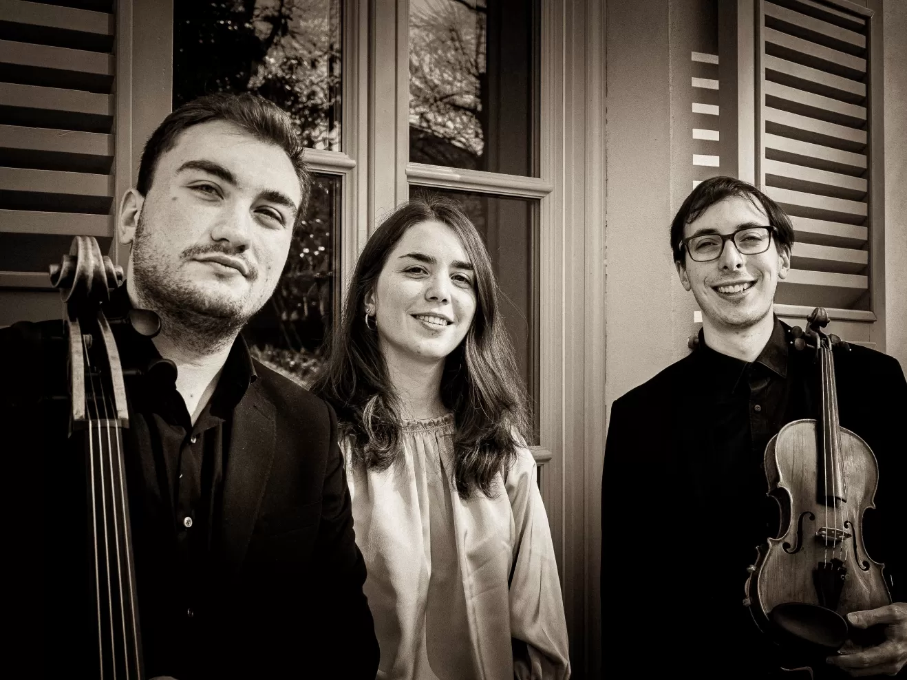 Die drei Musiker*innen des Trio Chimera lächelnd vor einem Haus