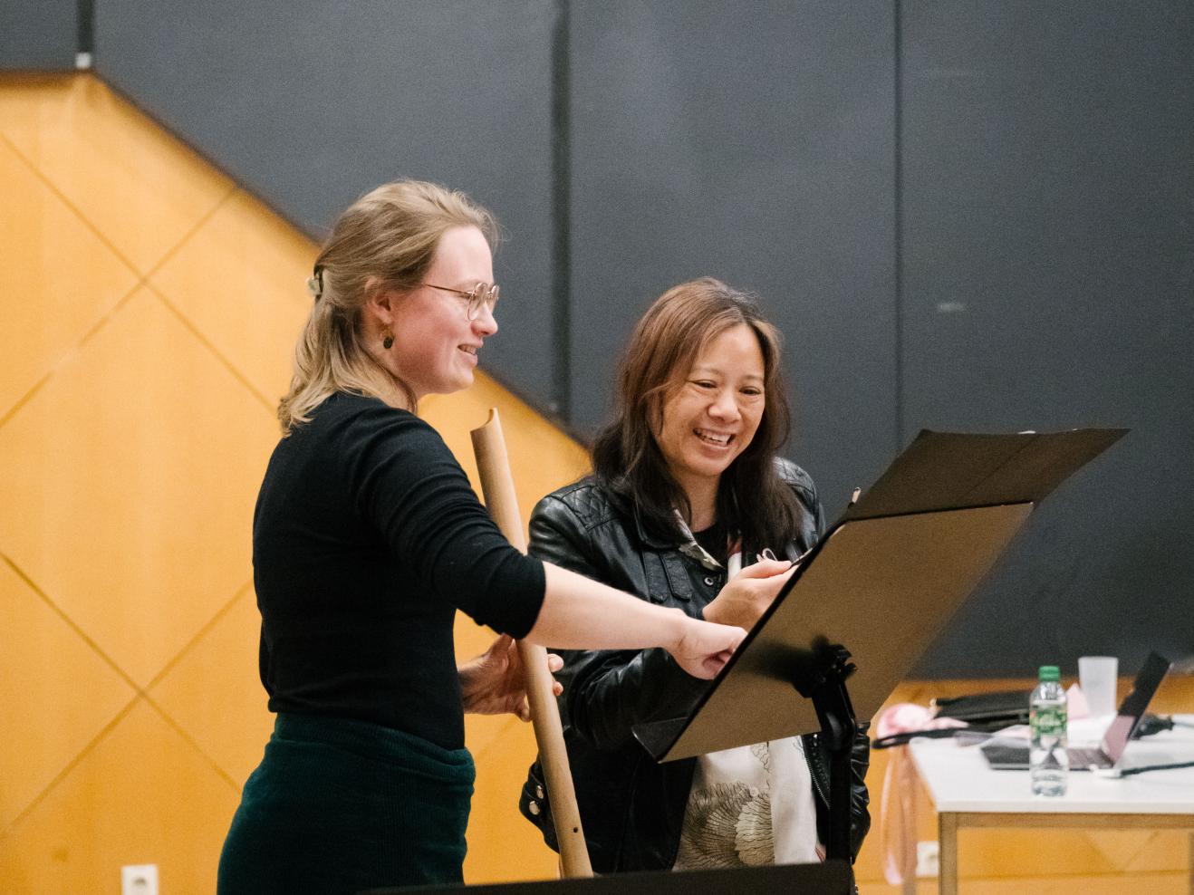 Stiftungsgastprofessorin Liza Lim mit einer Studentin, beide schauen zusammen auf Noten