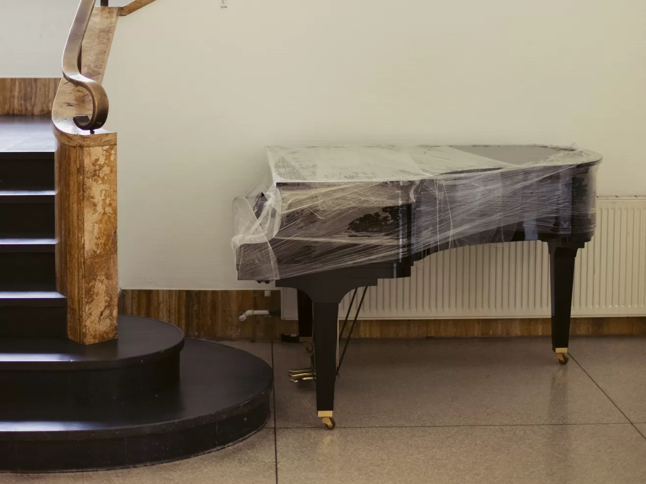 Ein eingehülltes Klavier steht neben einer Treppe.