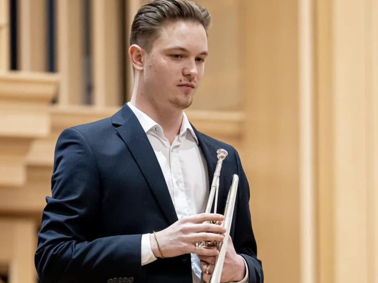 Levente Hanzlik steht auf der Bühne und hält die Trompete in der Hand.