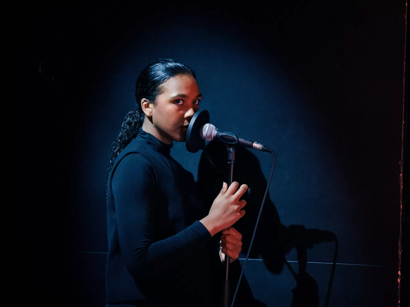 Rokhi Müller steht auf der Bühne und hält ein Mikro in der Hand