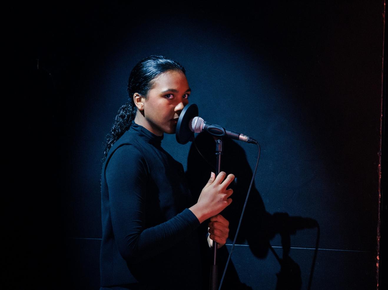 Rokhi Müller steht auf der Bühne und hält ein Mikro in der Hand