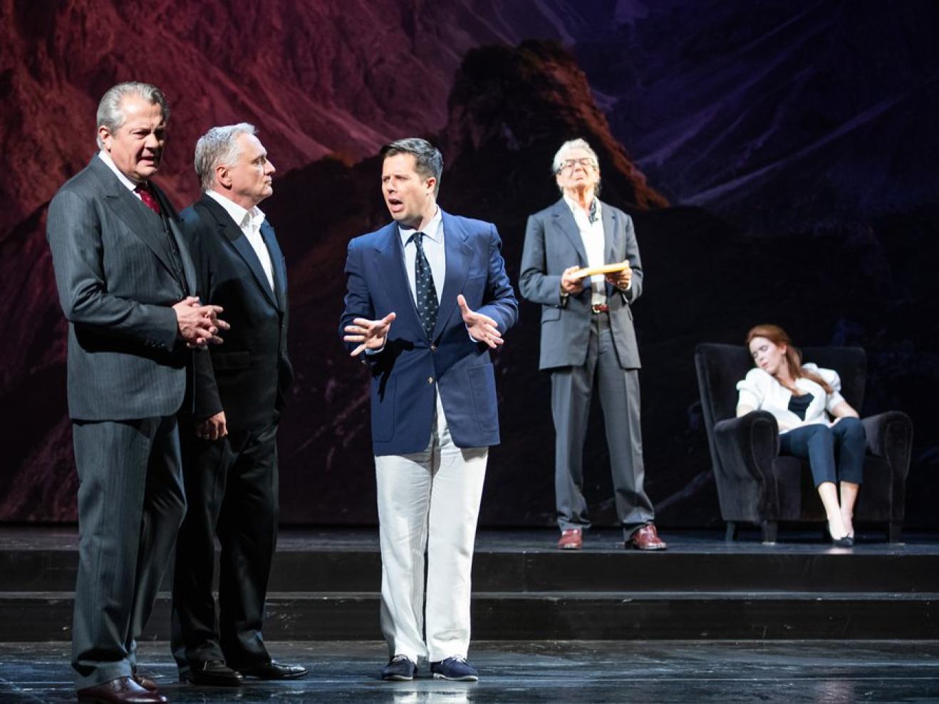 Viele Männer in Anzügen stehen auf der Bühne und reden miteinander.