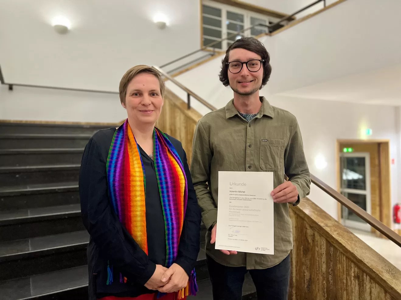 Prof. Christina Richter-Ibanez und Valentin Michel, der die Urkunde des Exzellenzpreises in der Hand hält