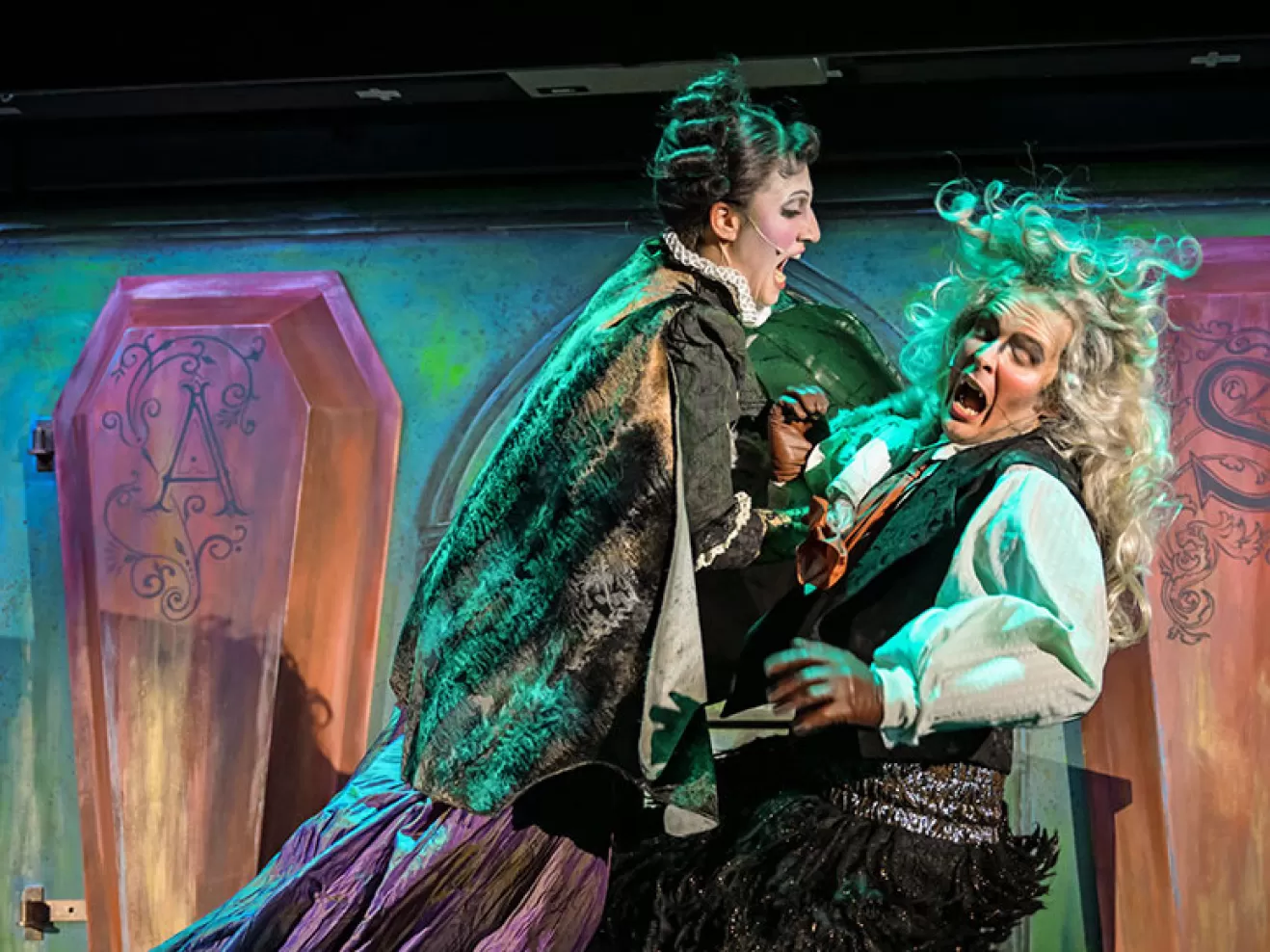 Zwei Menschen sind auf der Bühne, die eine Person springt auf die andere, erschrockene Person zu