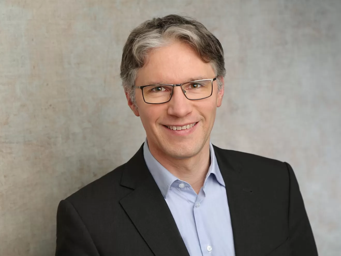 Portraiaufnahme von Jorin Sandau im Anzug vor weißem Hintergrund