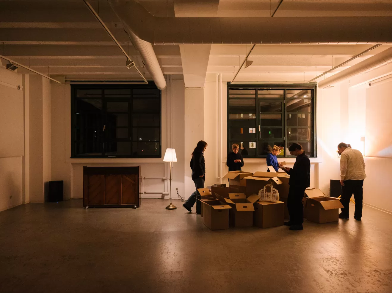 Leerer Raum, in dem Umzugskartons liegen, um die herum fünf Personen stehen.