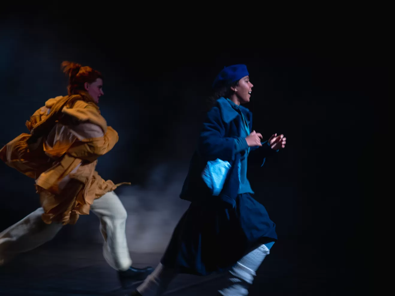 Zwei junge Frauen in Winterkleidung rennen.