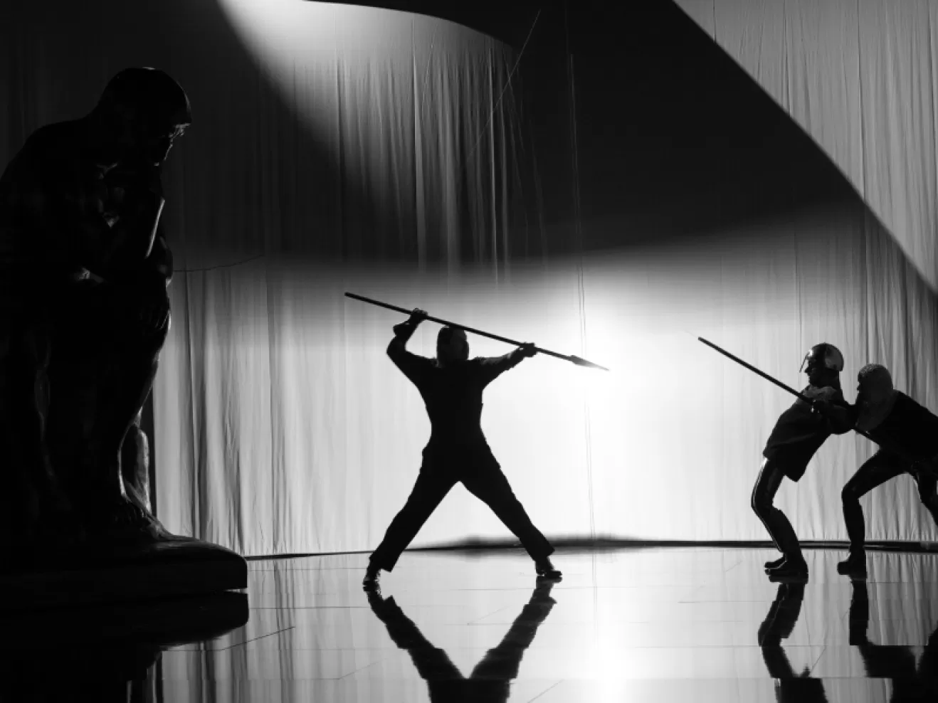 Drei Menschen die im Schatten einen Schwertkampf machen