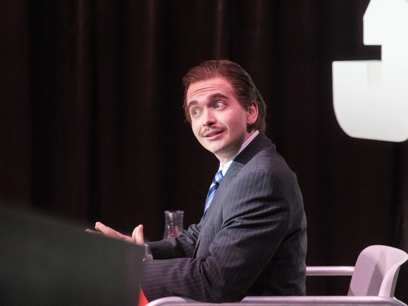 Mann in Anzug sitzt an einem Konferenztisch.