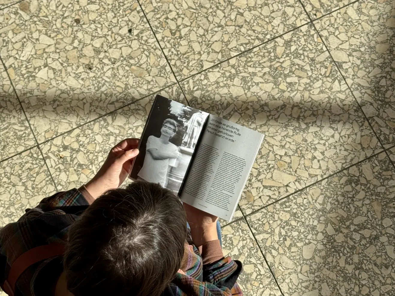Eine Person, die das Magazin Frankfurt in Takt liest, von oben gesehen.